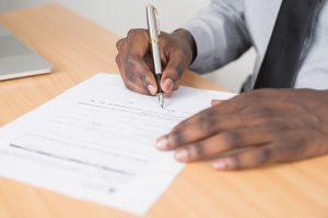 black mans hands signing paperwork